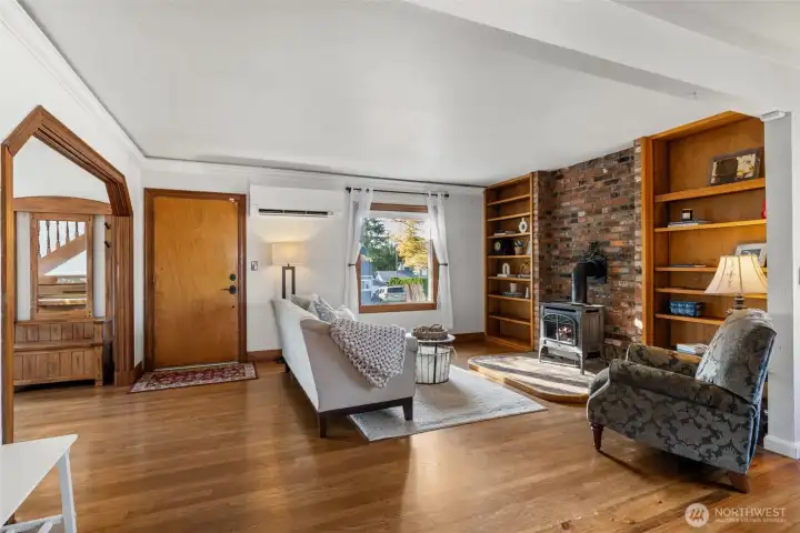 “Spacious living room with cozy gas stove, crown molding, and wood-wrapped windows.”