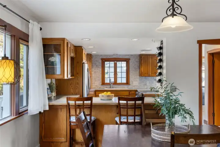 “Bright kitchen with a cozy breakfast nook surrounded by windows.”