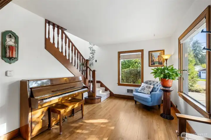 “Charming parlor with open railing staircase leading to the primary suite and third bedroom.”