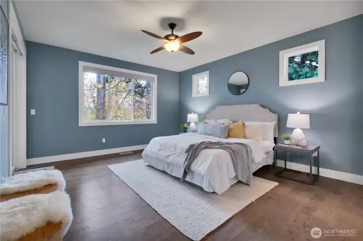 Serene primary suite with remote Hunter Douglas window coverings.  Engineered hardwood floors. Sliding door to porch on your left.  Bath to right.  Note clerestory windows above bed.