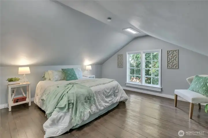 Large upper-level bedroom with dormer ceilings and large window