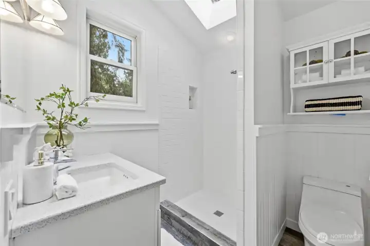 The skylight and window fill the primary bathroom with natural light.