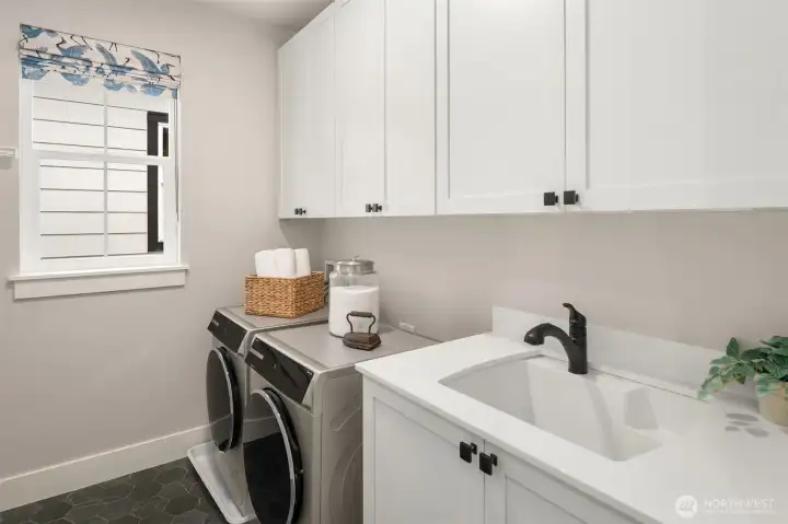 Convenient upstairs laundry room with built-in cabinetry and workspace.