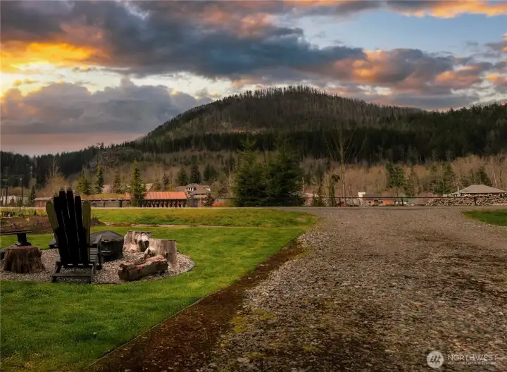 Front lawn features a custom fire pit lounge, complete with Adirondack Ski back chairs ~ designed for storytelling, fireside conversations, and roasting marshmallows beneath the mountain sky. Firepit blankets and extendable marshmallow sticks are neatly tucked away in a nearby storage bench.