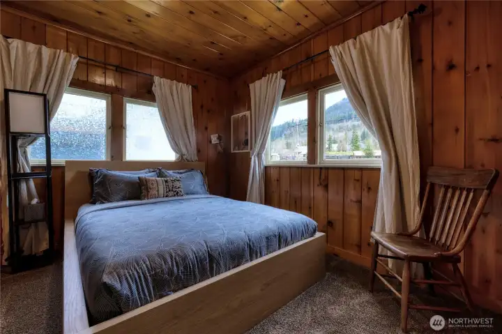 Bedroom 1of 2 features beautiful warm wood interior walls & ceiling, offering a serene cabin-inspired atmosphere for rest and relaxation.