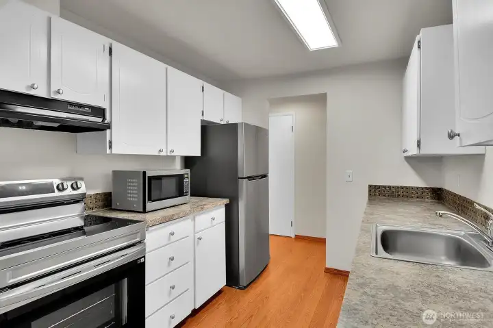 Efficient kitchen featuring freshly painted cabinets and sleek stainless steel appliances.