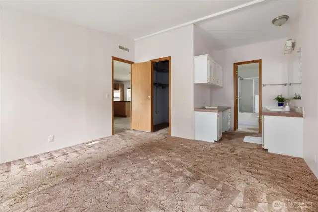 Walk in closet and a vanity area before the toilet shower with a dressing table and numerous cabinets