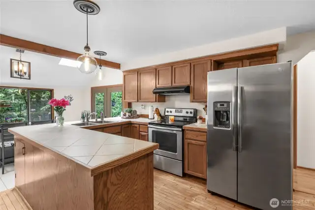 Kitchen – Stainless steel appliances, deep double sink, and skylit ceilings with wood beam accents