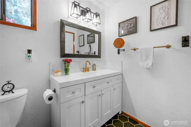 Main Level Bathroom – Updated vanity with sleek lighting, gold hardware, and stylish black hex tile.