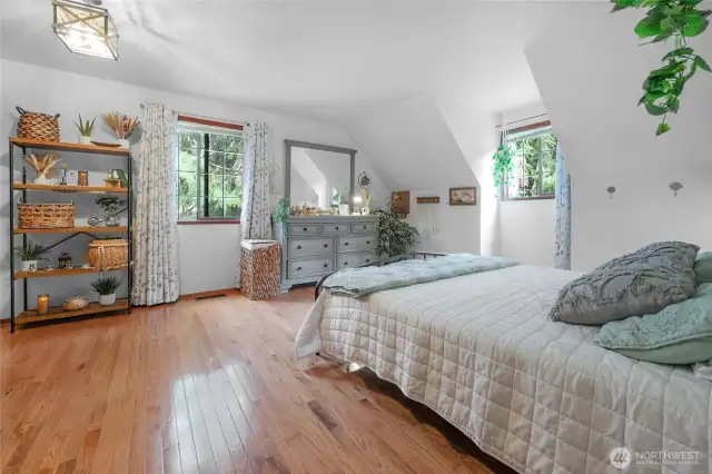 Primary Bedroom – Upstairs retreat with hardwood floors and treehouse-like views from every window.