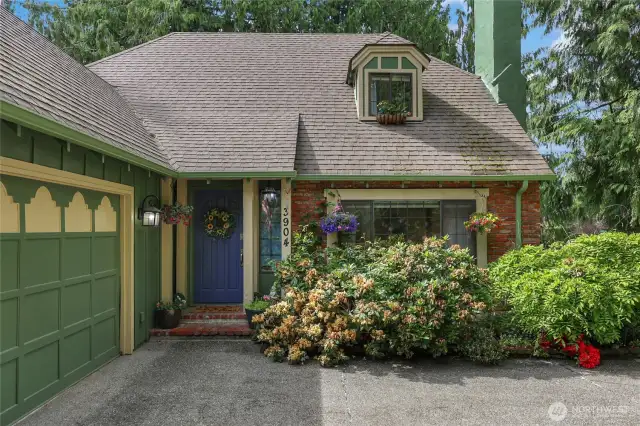 Enchanting Tudor-style entry surrounded by lush landscaping and a storybook setting.