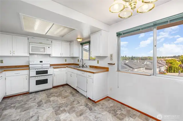 Kitchen features bright cabinetry, ample storage, sunlit windows, and room for extra storage!