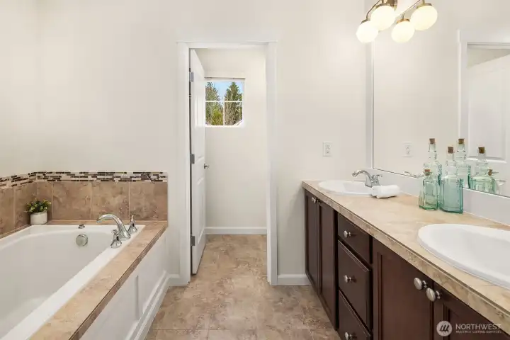 Primary suite bathroom with soaking tub, shower, double vanity, toilet room and walk-in closet. The whole interior was just painted and new light fixtures.