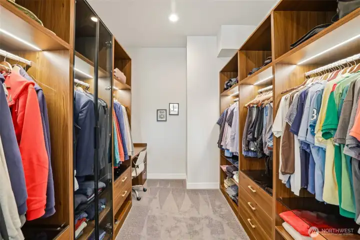Spacious walk in closet with custom built ins and  desk area.