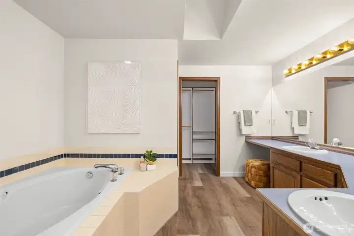 Large ensuite with soaking tub, dual vanity, toilet room, shower, and walk-in closet