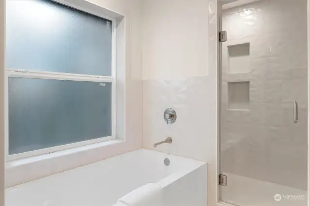 Primary tub and separate walk in shower with Dimensians ceramic wainscot in master bath and shower walls. Estate heavy glass framless shower door.