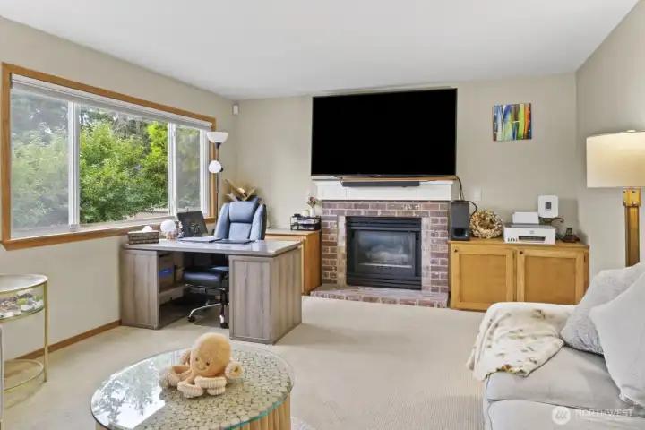 Enjoy serene garden views from the family room’s expansive rear window. A gas fireplace adds warmth and ambiance, easily operated with a wall switch, while neutral carpeting keeps the space comfortable and inviting.
