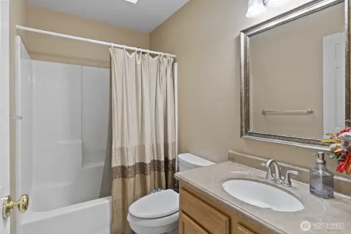 Upstairs, the main bathroom combines practicality and brightness with a low-maintenance tub surround, a solid countertop, and a skylight that floods the room with natural light.
