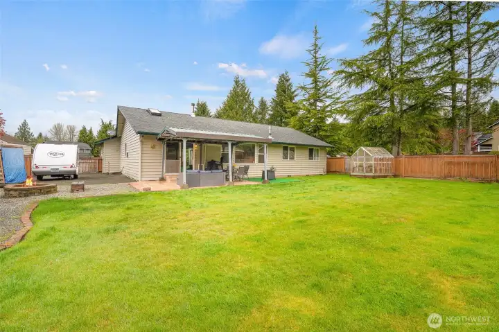 Greenhouse and powered 2-story shed offer space for projects, gardening, or creative pursuits.