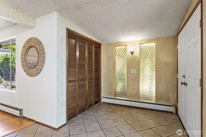 Twenty-seven feet of foyer. The house announces itself before you reach the living room. Original 1965 — pebbled glass sidelights, louvered closet doors, embossed tile floor.
