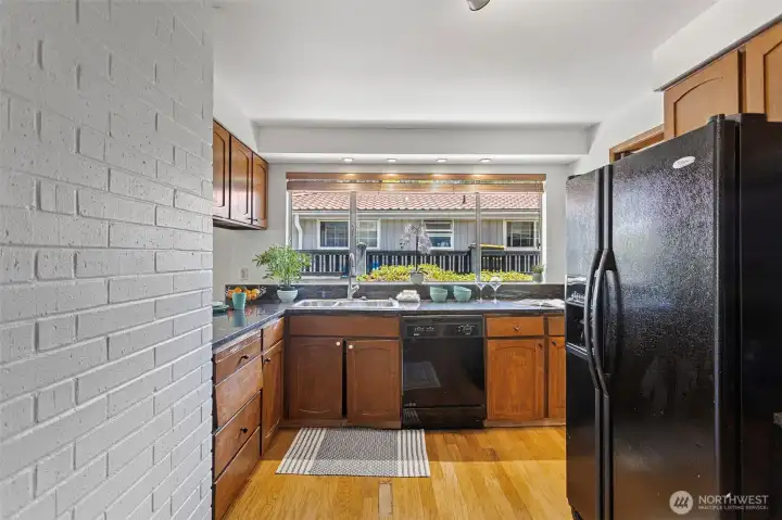 Brick accent wall, recessed lighting, double sink, big window. The bones are there.