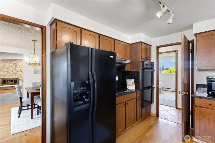 Double wall ovens, track lighting — and that's the stone fireplace through the doorway.