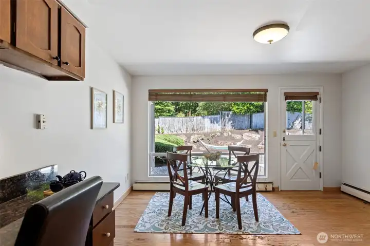 Second dining area with picture window to the back patio, exterior door, and a built-in desk in the corner.