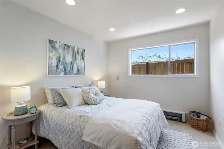 Lower bedroom 4 — west-facing window, recessed lighting, full closet with its own light, tile floor. Front of the lower level, just behind the garage.