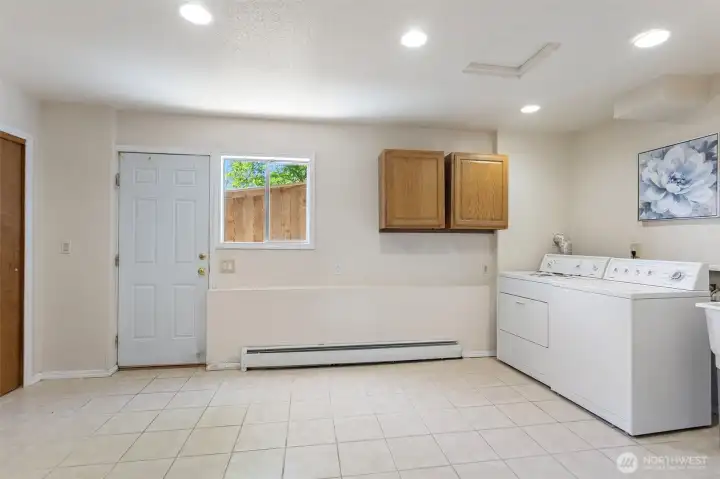 Large laundry room with exterior door, two closets with lights, upper cabinets, washer/dryer, recessed lighting. The start of a future second kitchen conversation for this level — buyer to verify all uses and permitting.