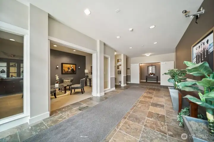 The 400 foyer offers gathering spaces to the left, elevators for below resident parking and resident mailboxes. Unit #115 is a short distance to the right on this main level.