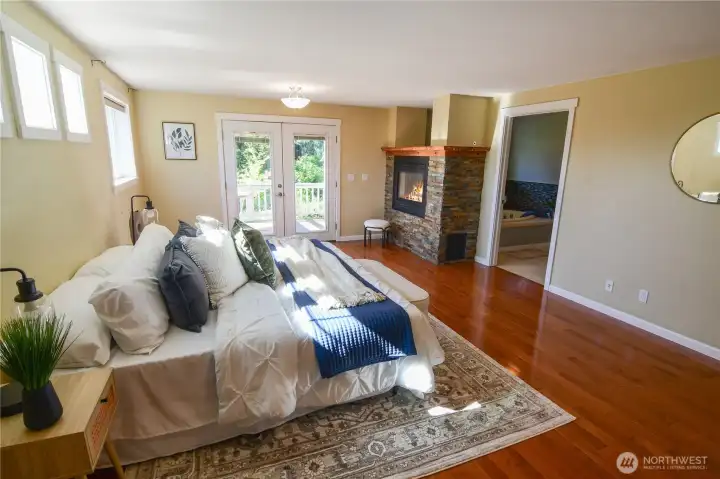Expanded primary suite has wood floors, lovely windows and french doors to your private deck for early morning coffee to enjoy. Luxury is yours with a double sided fireplace to enjoy from your bed and also from your bathtub.