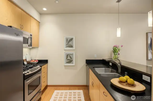 Sleek maple cabinetry is complemented by sustainable Paperstone counters and stainless appliances. The bar is an elegant quartz for subtle contrast.