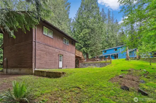 Backside of garage, lower level off to left is trail within the property. Gentle slope of the property from the garage with unfinished second floor, open area and two rooms.