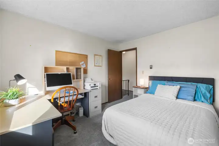 Alternate view of the primary bedroom showing workspace area and access to the hall.