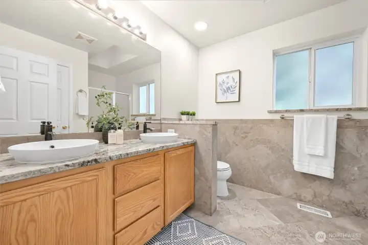 Primary bathroom with basin sinks atop granite counters.