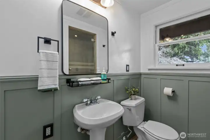 Main floor bathroom with deep shower and wainscotting.