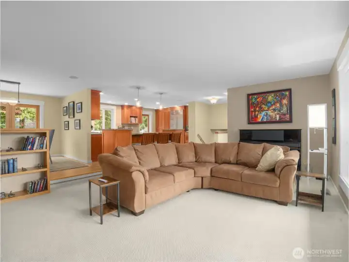 The open floor plan of the living room seamlessly connects with the dining and kitchen areas, creating a spacious atmosphere for entertaining. Natural light floods in through large windows.