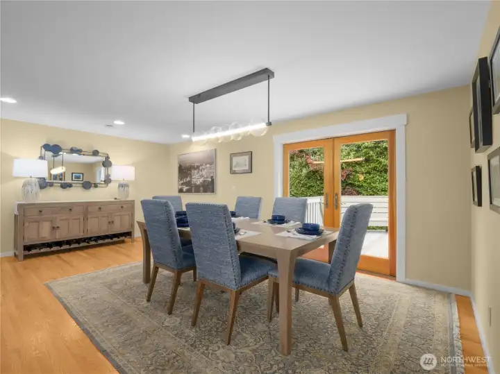The dining room features custom lighting that enhances its ambiance, complemented by elegant French doors that open to a spacious back deck, perfect for dining Al Fresco.