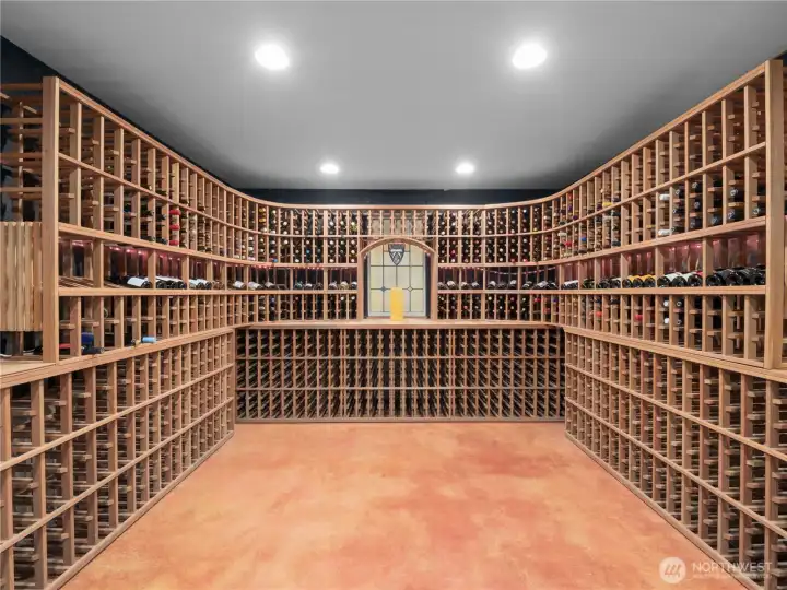 Discover a fully furnished 1400-bottle wine cellar through the hidden entrance, featuring a tasting area, custom polished concrete floor, naturally cooled for optimal storage, plus a spacious hidden storage area. Perfect for wine enthusiasts!