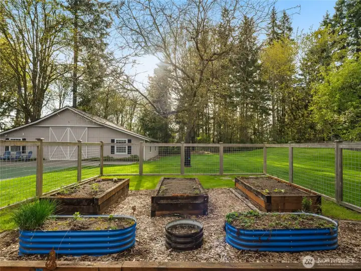 The fully fenced garden boasts six custom raised beds, providing ample space for planting. A lovely grass and flagstone patio complements the flower beds, creating a serene outdoor oasis.