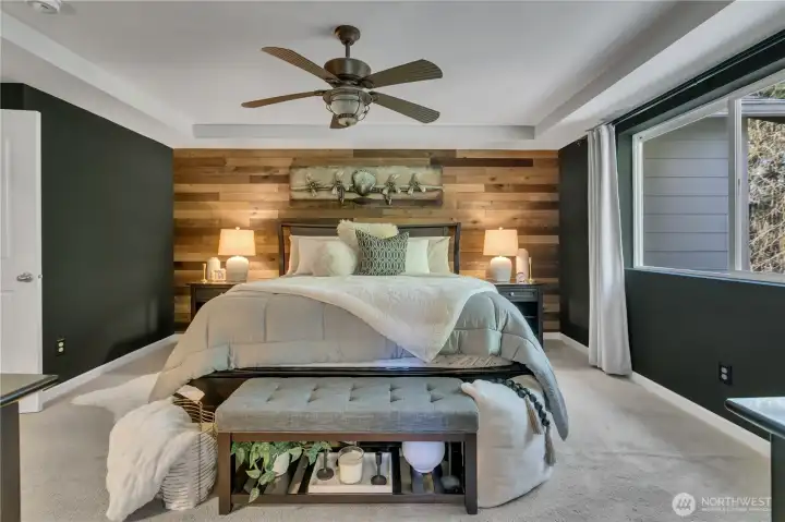 Ceiling fan and accent wall in primary bedroom