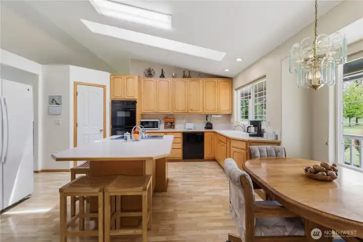 Farm style eat in kitchen with island cook top, double ovens, new dishwasher, maple cabinets, solid surface floors, skylight, and huge pantry.