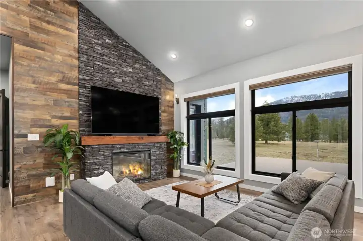 The heart of the home features a floor-to-ceiling stone fireplace, vaulted ceilings, and oversized windows that frame the surrounding natural beauty. The heart of the home features a floor-to-ceiling stone fireplace, vaulted ceilings, and oversized windows that frame the surrounding natural beauty.