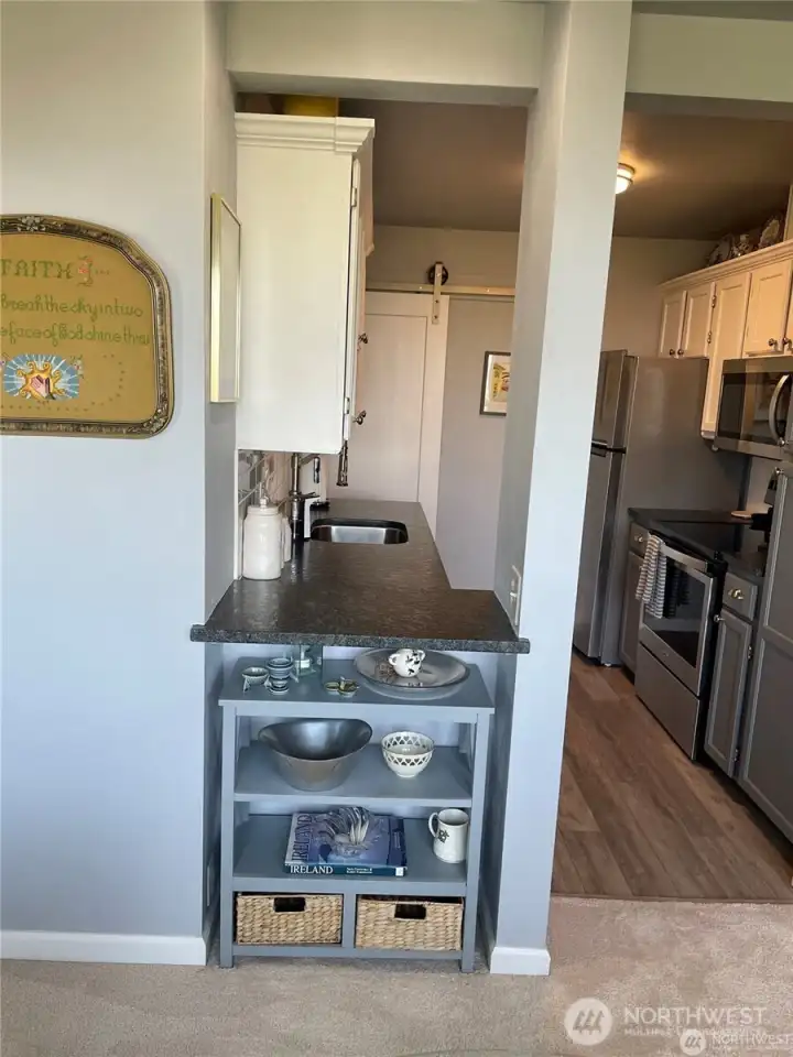 This is a view of the kitchen from the dining area. There is a cute shelf area and you can see the kitchen is not small