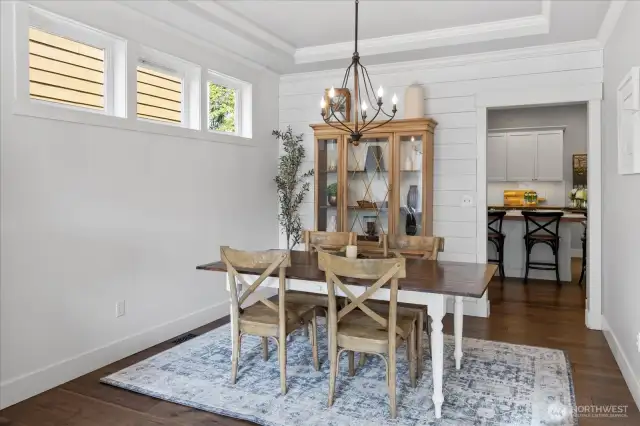Dining room with coved ceilings, shiplap, 3 inch baseboards, custom lighting, and access to the kitchen.