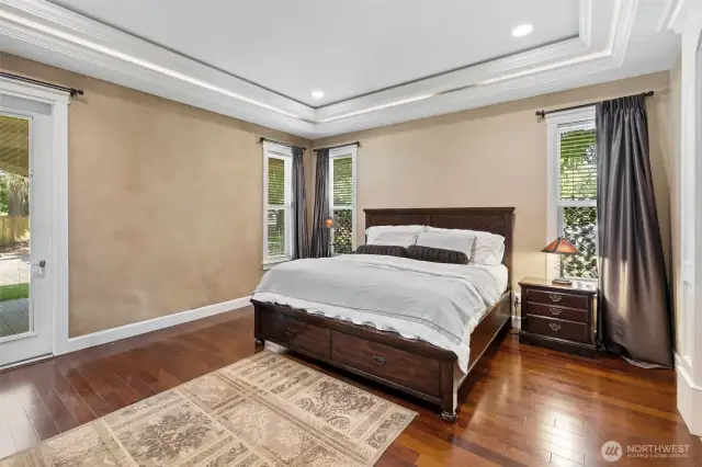 Main floor Primary bedroom with all the trimwork, beautiful floors, and also a door leading out to the covered patio!