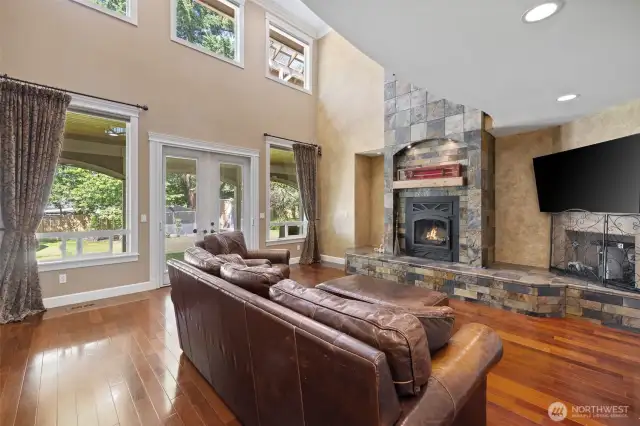 Vaulted Ceilings reach high with walls of windows blending in the beautiful yard.  Slate Stone fireplace with art niches embedded in.  French doors lead to the covered patio!