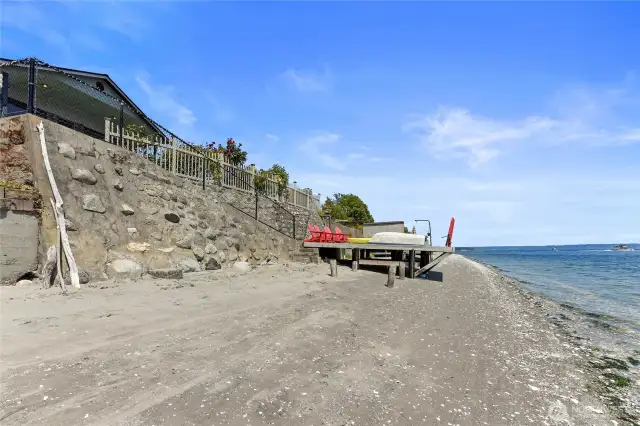 Sandy beach, waterside dock with davit, moorage buoy is straight out in the water.