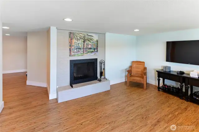Rec room with wood burning fireplace, vinyl planked floors.