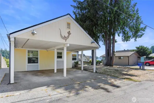 The street side carport has room for two cars with storage overhead. One open parking spot is right there too, then the driveway to the Main Beach House is next to the trees.